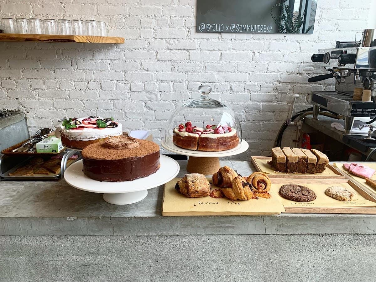 A white bakery tray holds an assortment of pastries, including a sugar doughnut, hot dog bun, and savory pork floss bread in front of a display case.